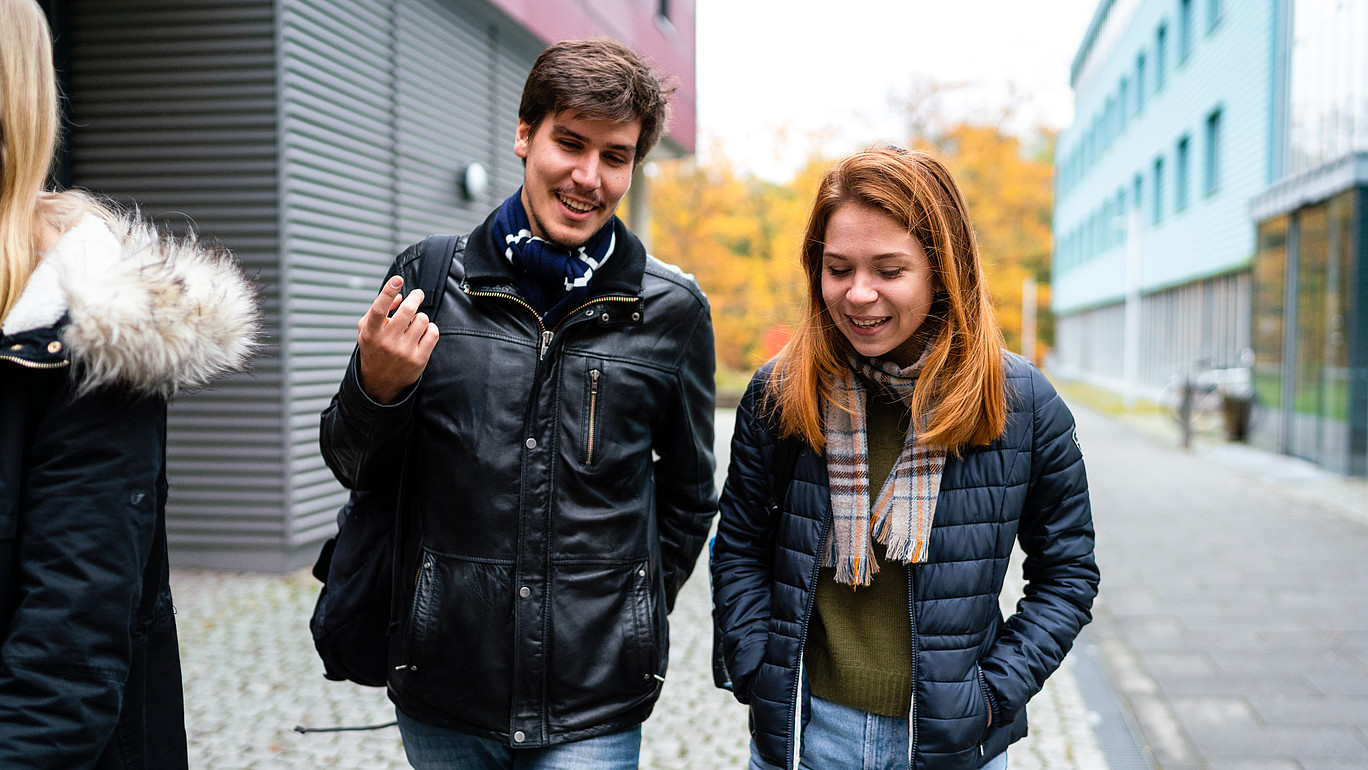 Ein Student und eine Studentin laufen zwischen zwei Gebäuden auf dem Görlitzer Campus entlang.