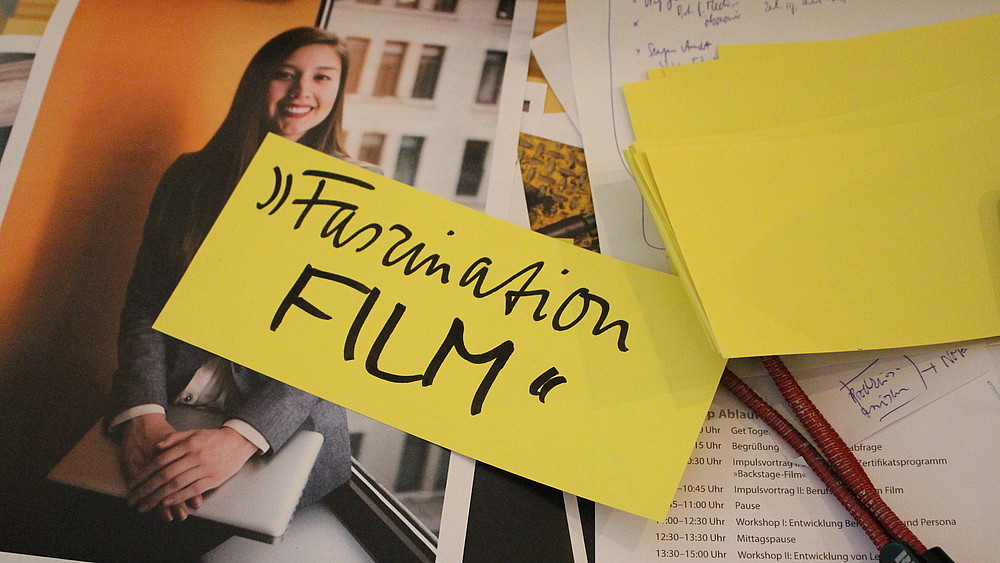 Ein Notizzettel mit der Aufschrift Faszination Film liegt auf Workshopmaterialien auf dem Tisch.