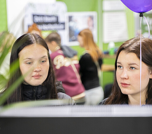 Zwei Schülerinnen mit dunkeln Haaren schauen sich um.