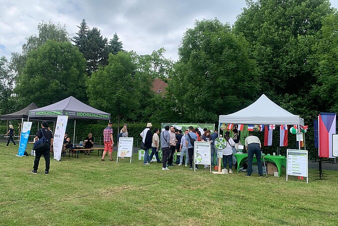 Teilnehmende feiern auf der Festwiese zwischen Pavillons.