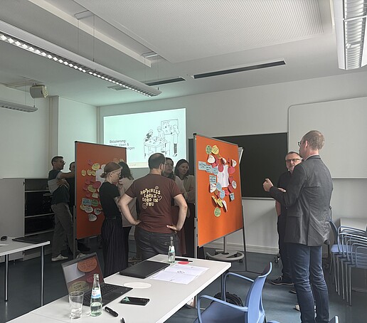 Teilnehmer stehen um Pinnwände und tauschen sich aus