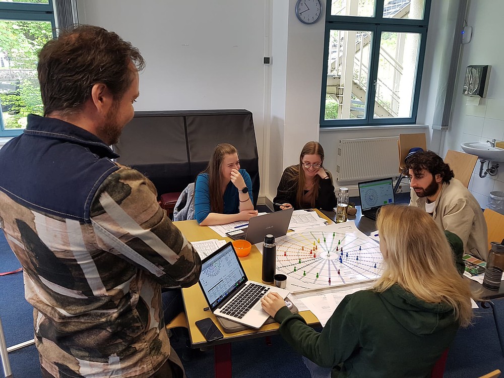 Studierende sitzen um ein Brettspiel