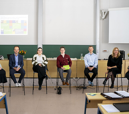 Auf Stühlen sitzen Teilnehmende der Diskussionsrunde.