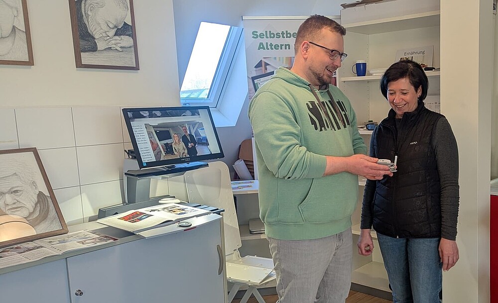 2 Personen stehen im Labor. Ein Mann zeigt einer Frau eine Technologie aus dem Labor.