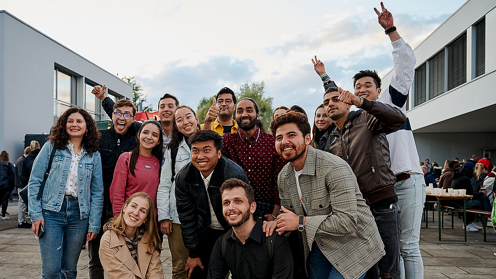 Eine Gruppe Studierender steht jubelnd auf dem Zittauer Campus.