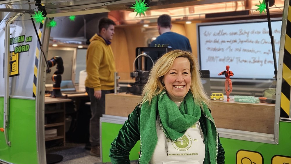 Die Prorektorin steht vor dem geöffneten AirStream-Anhänger.