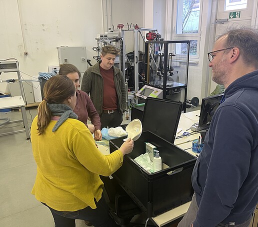 4 Mitarbeitende schauen sich verschiedene Materialien an