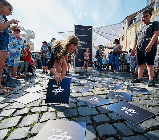 Kinder legen DLR-Karten auf Pflastersteine.
