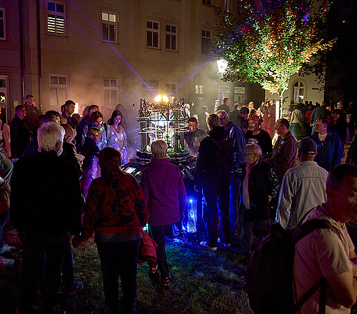 Besucher stehen um eine Leuchtinstallation herum.