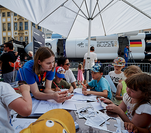 Kinder basteln an einem Marktstand.