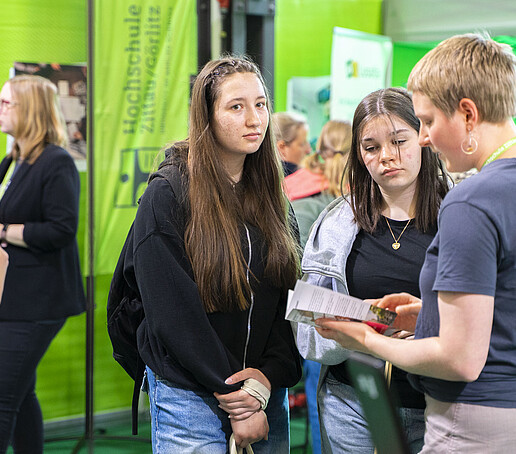 Studieninteressierte unterhalten sich mit einer Studentischen Hilfskraft.