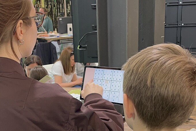 Junge Frau zeigt einem Kind Funktionen an einem Tablet