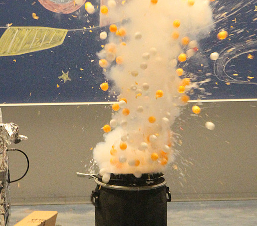 Aus einem Fass steigen gelbe und weiße Bälle und Dampf nach oben.