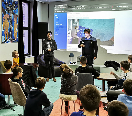 Kazimierz Przybysz und Daniel Winkler halten vor einer Gruppe Schüler*innen einen Vortrag.