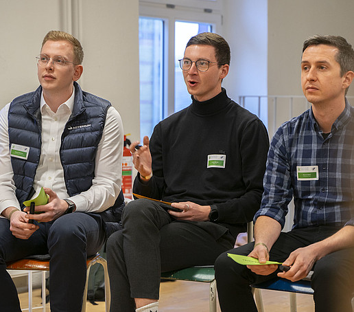 Drei Workshop-Teilnehmende sitzen nebeneinander auf Stühlen.