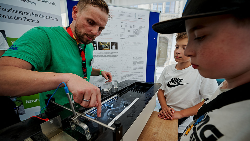 Ein HSZG-Mitarbeiter erklärt Schüler am Stand Strömungstechnik.