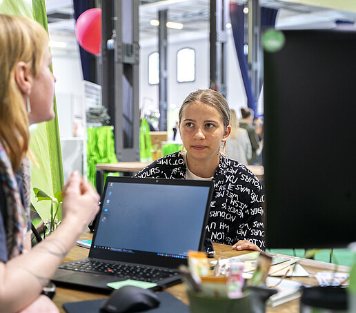 Eine Mitarbeiterin im Gespräch mit einer jungen Besucherin.
