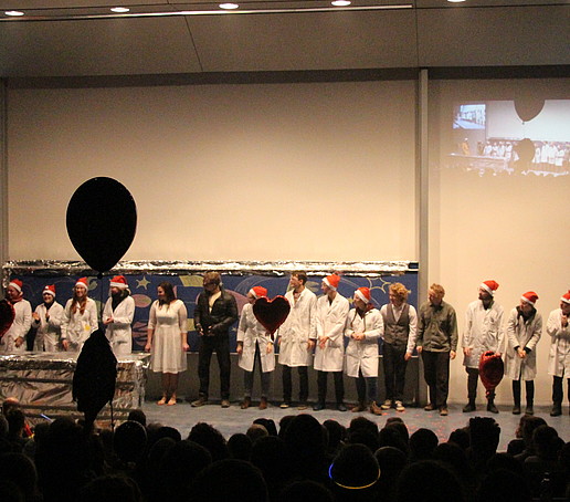Auf der Bühne steht das gesamte Team der Chemie-Schauvorlesung mit Weihnachtsmützen.