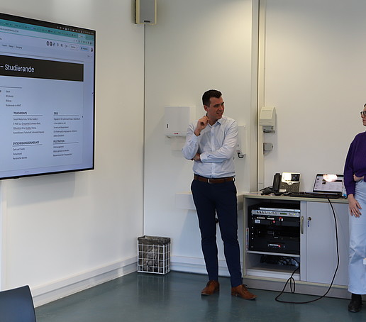 Zwei Studierende hören einem Agenturmitarbeiter zu.