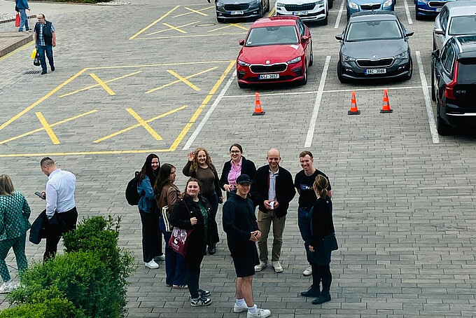 Eine Gruppe Studierender steht auf einem Parkplatz.