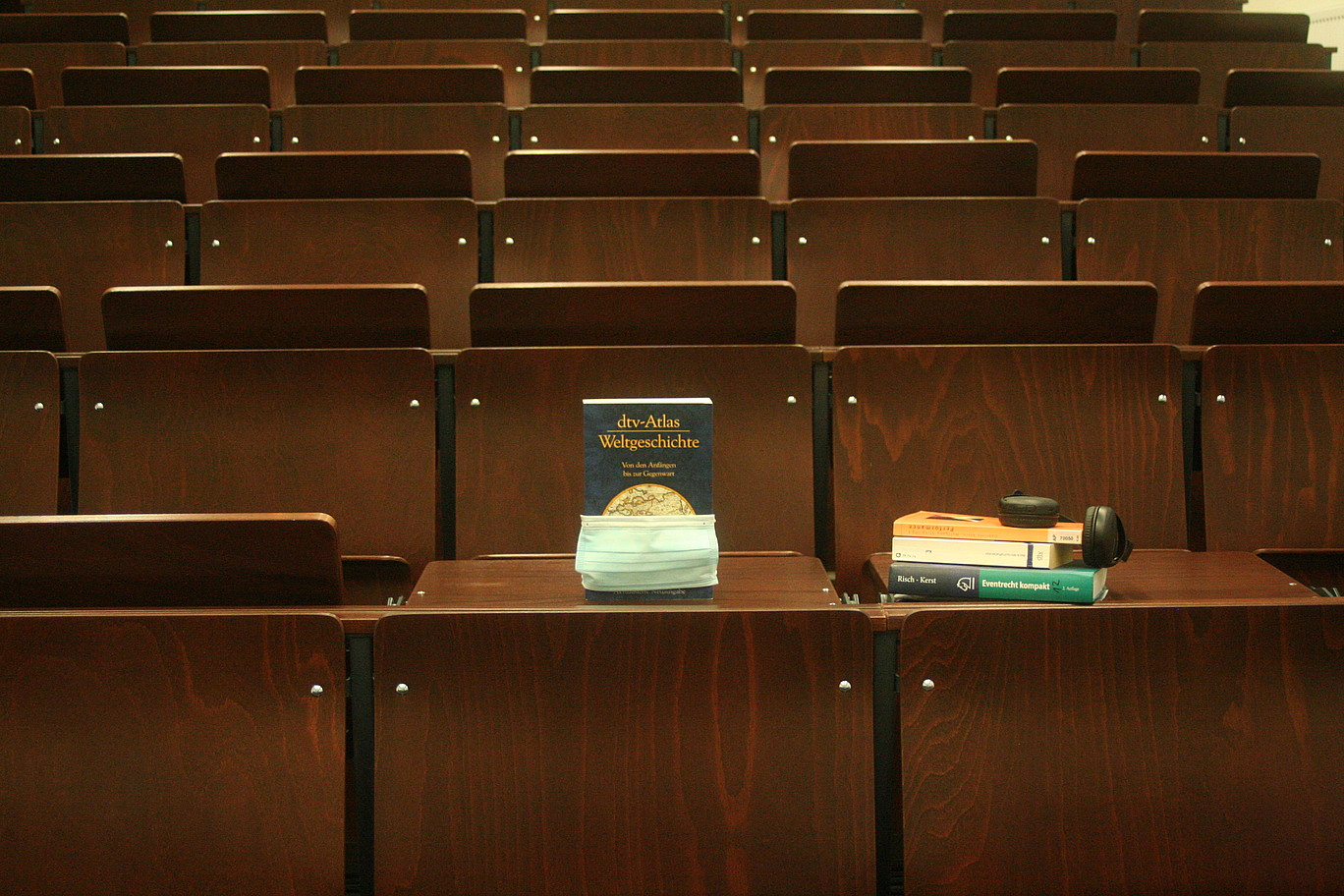 Hörsaal mit Büchern und Maske auf dem Tisch