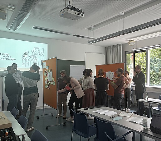 Teilnehmer stehen um Pinnwände und tauschen sich aus