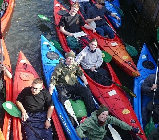 Studierende sitzen in Paddelbooten.