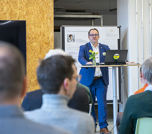 Der Rektor hält am Stehtisch eine Rede.