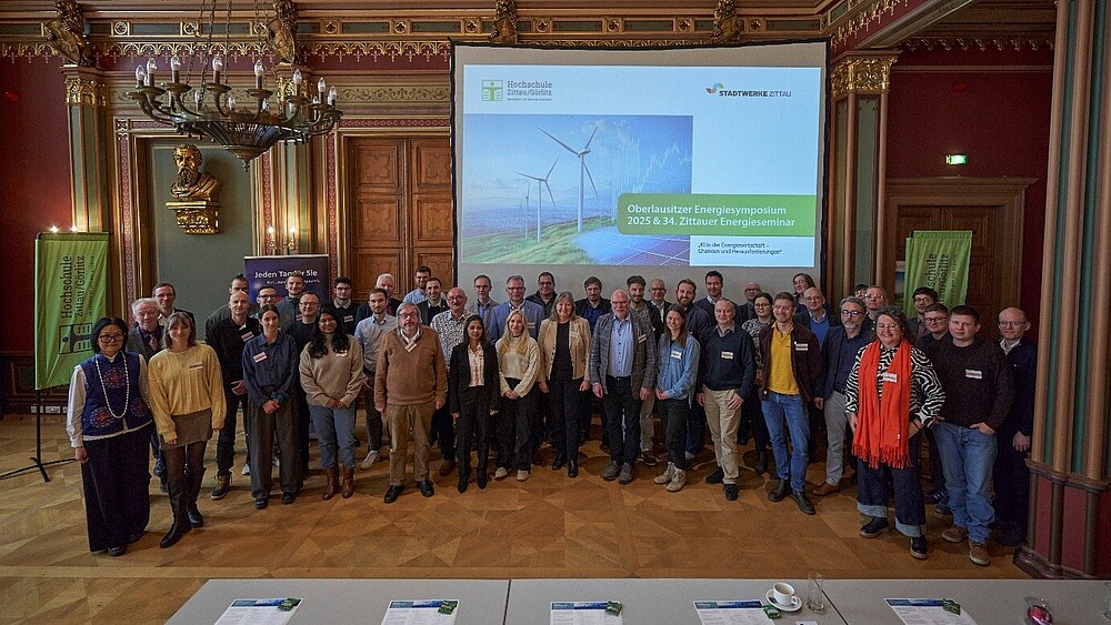 Im Bürgersaal des Zittauer Rathauses steht eine Gruppe Menschen nebeneinander und lächeln in die Kamera.