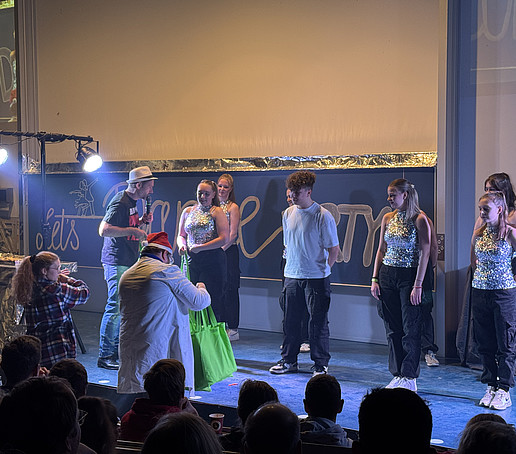 Eine Tanzgruppe bekommt als Dankeschön grüne HSZG-Beutel überreicht.