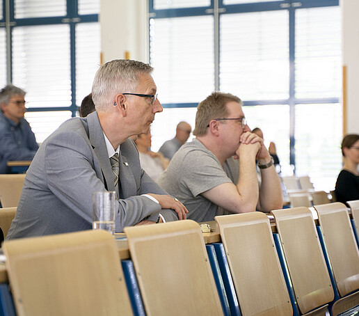 Zuhörer sitzen auf Sitzreihen im Vorlesungssaal.