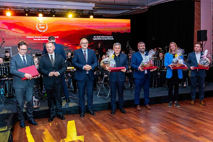 Teilnehmende mit Präsenten stehen vor der Bühne.