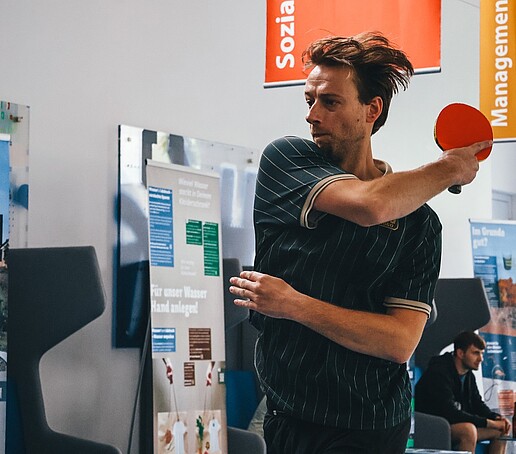 Ein Tischtennisspieler holt mit seinem Schläger zum Schlag aus.