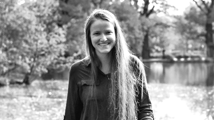 Stella Silbermann läuft lächelnd einem Bootssteg an einem See entlang.