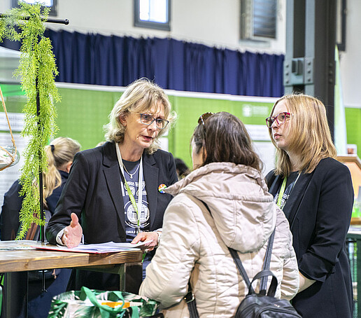 Zwei Mitarbeiterinnen beraten eine Besucherin am Personalstand.