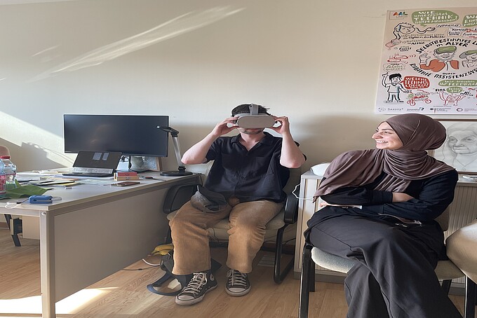 junger Mann testet VR-Brille und junge Frau sieht zu