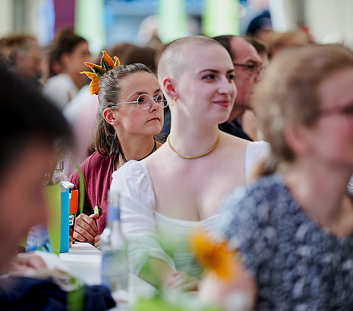 Gäste im Publikum auf vollen Sitzreihen.