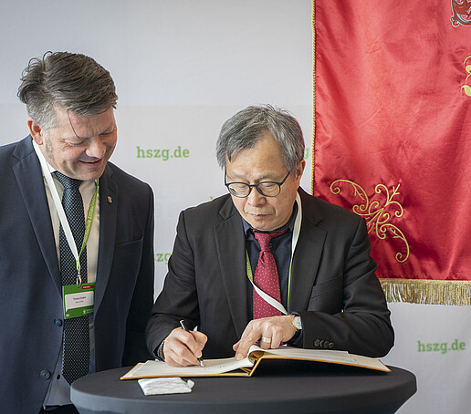 Thomas Zenker und Jhy-Wey Shieh beim Eintrag ins Gästebuch, im Hintergrund die Zittauer Stadtflagge.