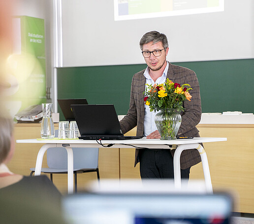 Ein Professor hält eine Rede am Rednerpult im Vorlesungssaal.