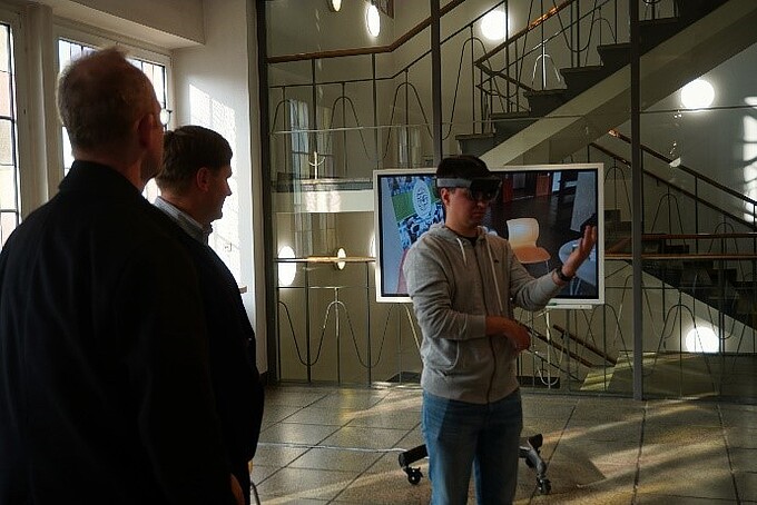 Ein Mitarbeiter trägt eine AR-Brille, andere Mitarbeiter schauen ihm zu.