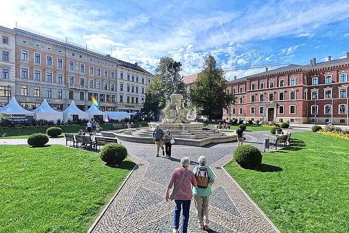 Besucher laufen auf den Brunnen mitten auf den Görlitzer Postplatz zu.
