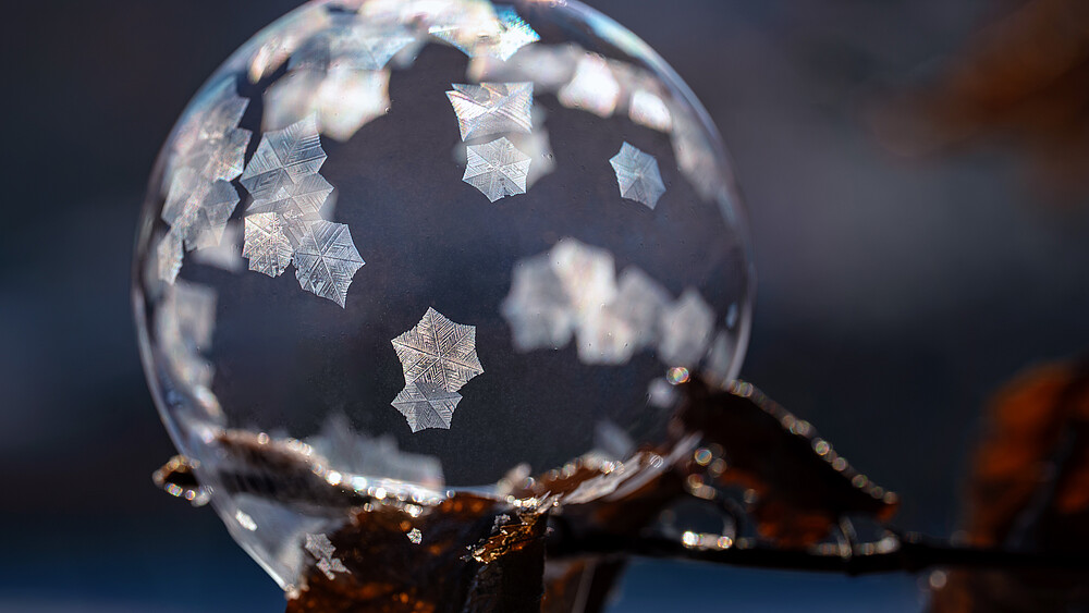 Eine eingefrorene Seifenblase zeigt viele Kristallformen an der Oberfläche.
