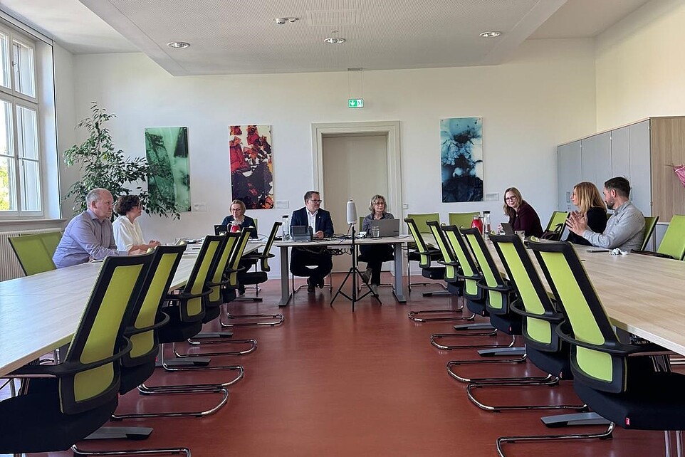 Mitglieder der Personalentwicklungskommission sitzen an Konferenztischen im Senatssaal der HSZG und besprechen sich. An der Stirnseite sitzt der Rektor.