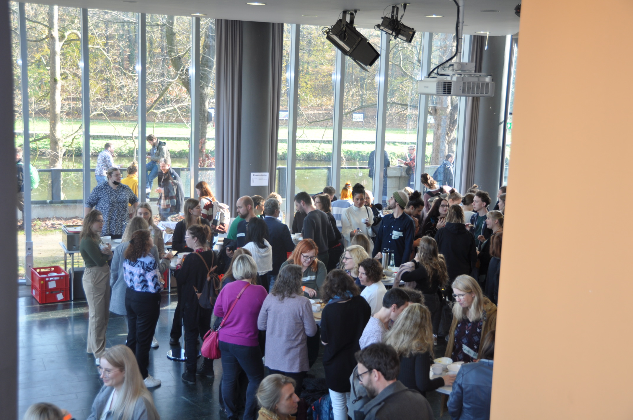 Studierende und Alumni versammeln sich im Foyer zum Essen
